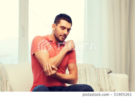 unhappy man suffering from pain in hand at home unhappy man suffering from pain in hand at home 31905261