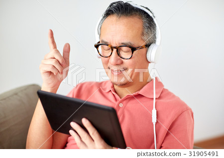 man with tablet pc and headphones at home man with tablet pc and headphones at home 31905491