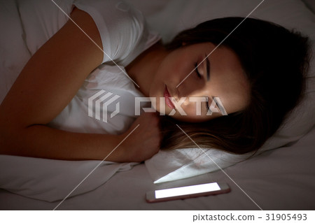 woman with smartphone sleeping in bed at night 31905493