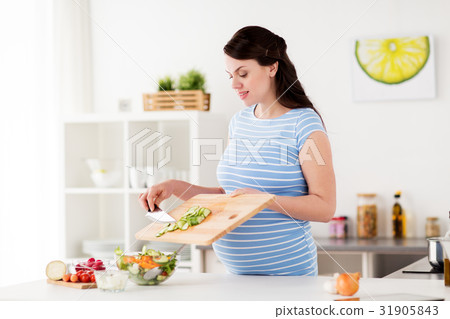 pregnant woman cooking vegetable salad at home 31905843