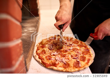 cook hands cutting pizza to pieces at pizzeria 31905849