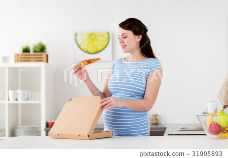 happy pregnant woman eating pizza at home kitchen 31905893