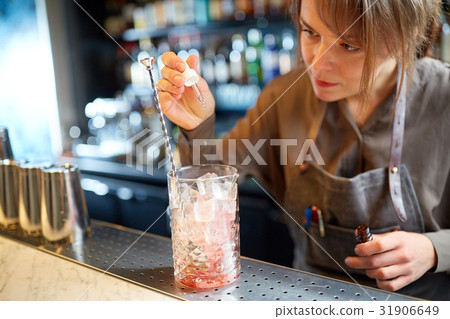 bartender adding essence to cocktail glass at bar 31906649