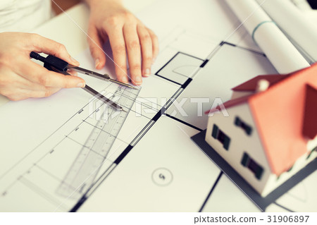 close up of hands with compass measuring blueprint 31906897