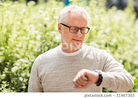 senior man checking time on his wristwatch senior man checking time on his wristwatch 31907303