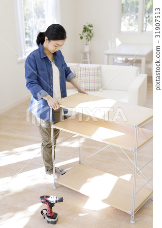 A woman assembling a shelf 31907513