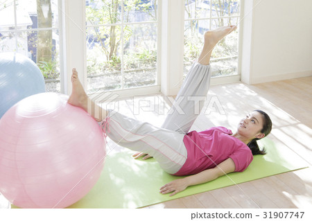 A woman who puts his feet on balance ball 31907747