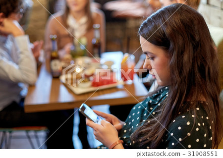 woman with smartphone and friends at restaurant 31908551