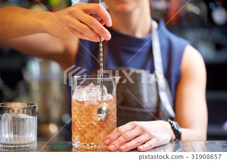 bartender with cocktail stirrer and glass at bar 31908657