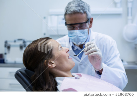 Dentist examining a young patient with tools Dentist examining a young patient with tools 31908700