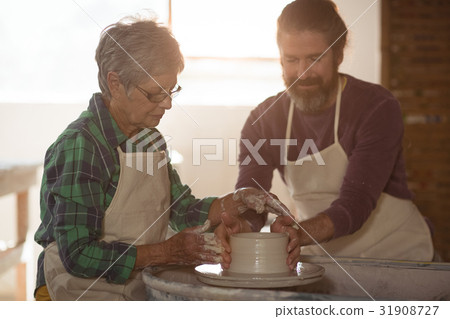 Male potter assisting female potter 31908727
