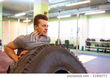 man doing strongman tire flip training in gym 31908771