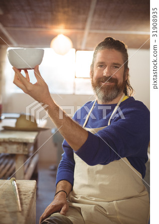 Potter holding bowl in workshop 31908935
