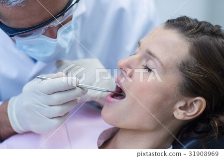 Dentist examining a patient with tools 31908969