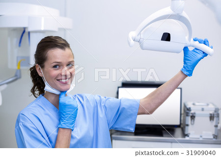 Portrait of dental assistant adjusting light Portrait of dental assistant adjusting light 31909040