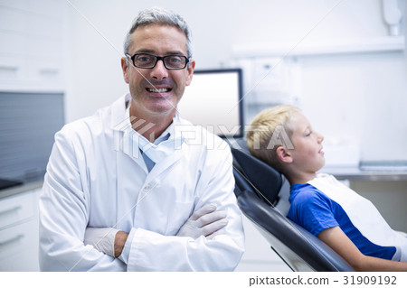 Portrait of smiling dentist standing with arms crossed Portrait of smiling dentist standing with arms crossed 31909192