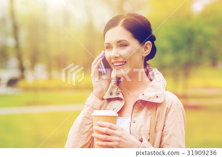 smiling woman with smartphone and coffee in park 31909236