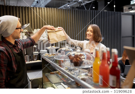 woman taking paper bag from seller at cafe 31909628
