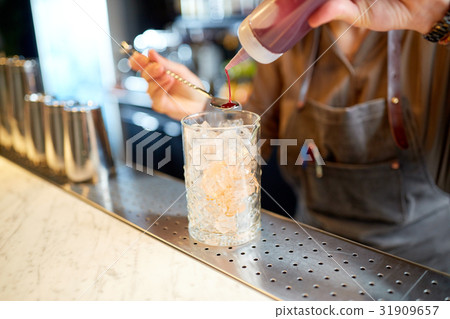 bartender with cocktail stirrer and glass at bar 31909657