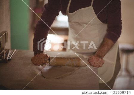 Male potter molding clay with rolling pin 31909714