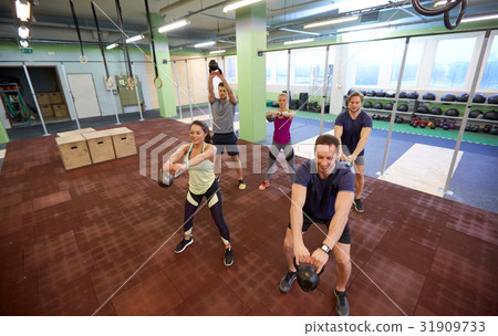 group of people with kettlebells exercising in gym 31909733