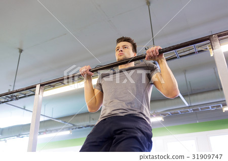 man exercising on bar and doing pull-ups in gym 31909747