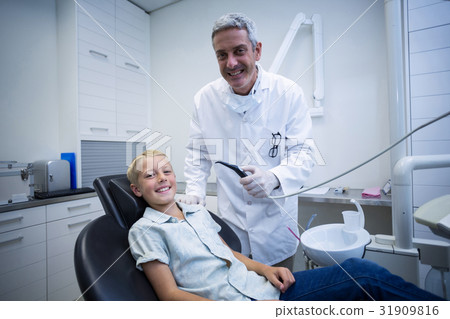 Dentist examining a young patient with tools 31909816