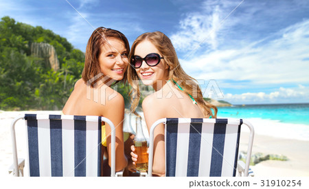 happy young women with drinks sunbathing on beach happy young women with drinks sunbathing on beach 31910254