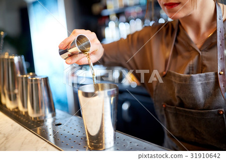 bartender with cocktail shaker and jigger at bar 31910642