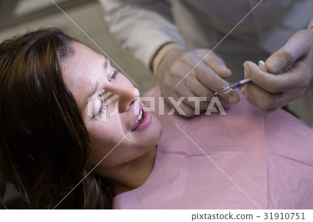 Dentist injecting female patient 31910751