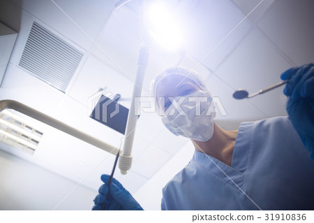 Dental assistant in surgical mask holding dental tools 31910836
