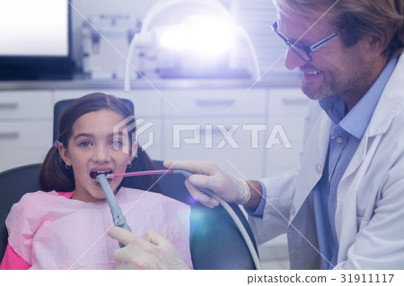 Dentist examining a young patient with tools Dentist examining a young patient with tools 31911117