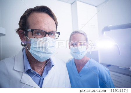 Portrait of dental assistant and dentist wearing surgical mask Portrait of dental assistant and dentist wearing surgical mask 31911374