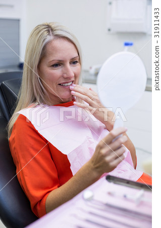 Patient checking her teeth in mirror 31911433