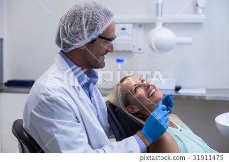Male dentist interacting with female patient 31911475