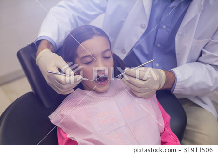 Dentist examining a young patient with tools 31911506