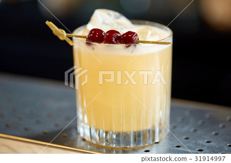 glass of cocktail with cherries at bar 31914997