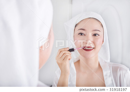 woman looking in mirror and applying red lipstick on her lips 31918197