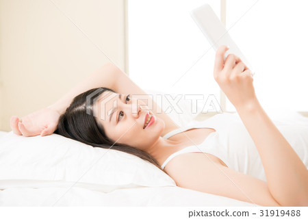 asian woman reading with digital tablet on bed asian woman reading with digital tablet on bed 31919488