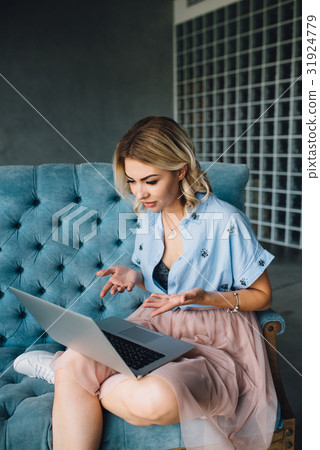 Happy woman sitting on couch using her laptop 31924779