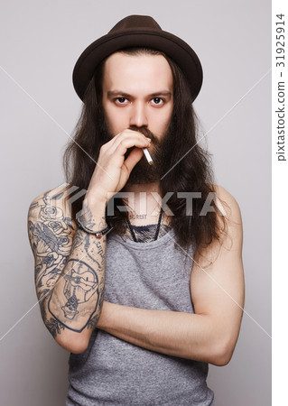 The guy in hat is smoking and looking The guy in hat is smoking and looking 31925914