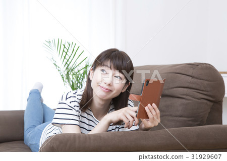 A young lady who operates a smartphone lying on the sofa 31929607