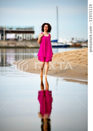 Young woman in a red dress and curly hair on the water coast 31933119