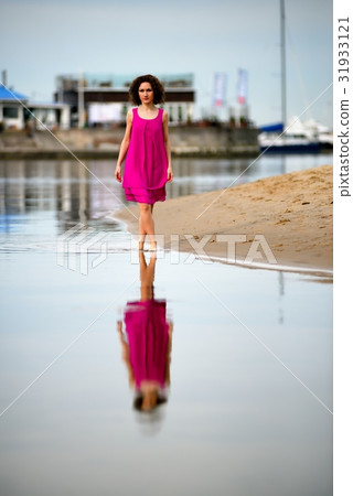 Young woman in a red dress and curly hair on the water coast 31933121
