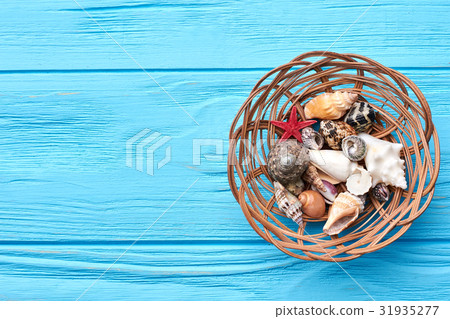 Seashells in basket, blue background. 31935277