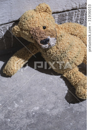 Old plush toy on the concrete floor. 31936033