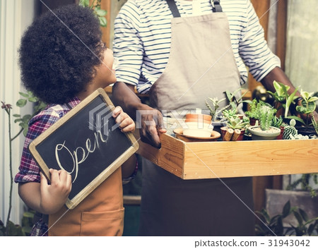 Man Carrying Plants Standing With Son Showing Open Sign 31943042