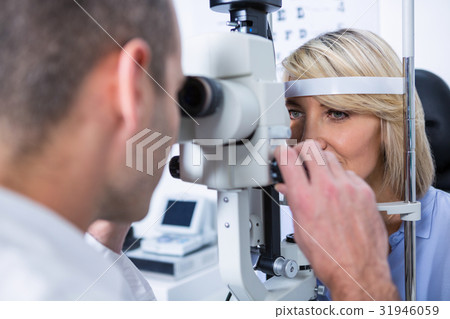 Optometrist examining female patient on slit lamp 31946059