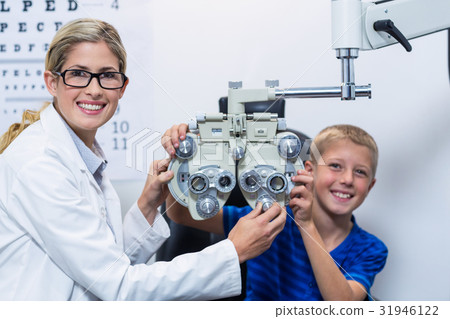 Optometrist and young patient smiling while under going eye test Optometrist and young patient smiling while under going eye test 31946122