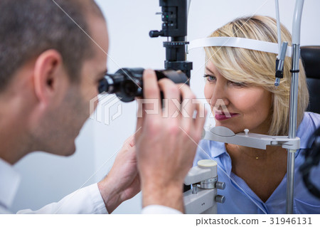 Optometrist examining female patient on slit lamp 31946131